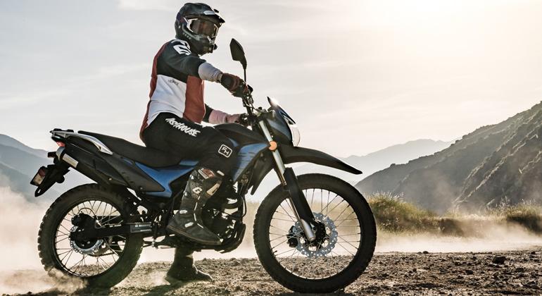 На изображении показан велосипед Enduro, стоящий вертикально с гонщиком на нем. На фото хорошо видно, что у мотоцикла высокая посадка